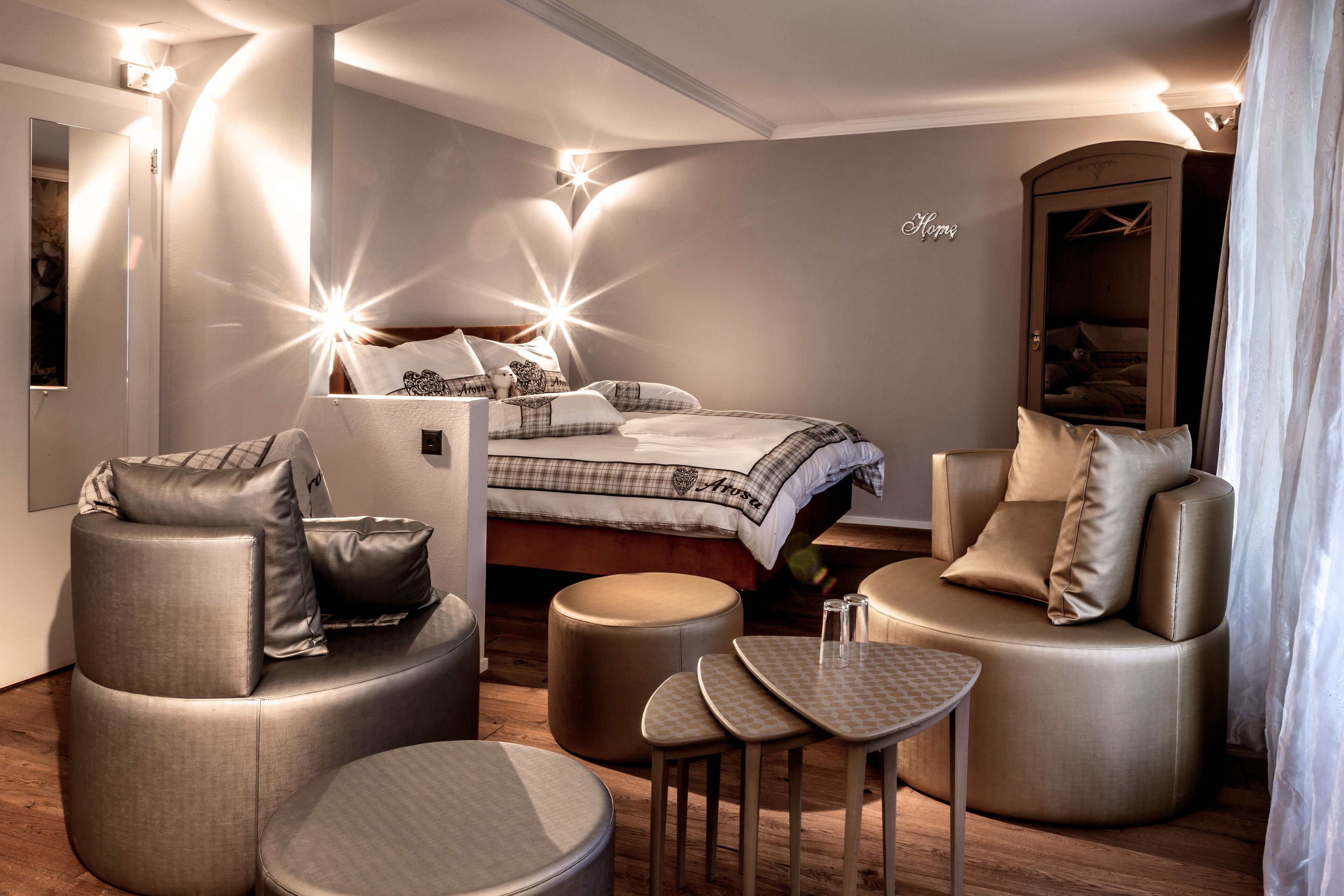 Un dormitorio moderno con una cama, dos sofás, una mesita y un armario.