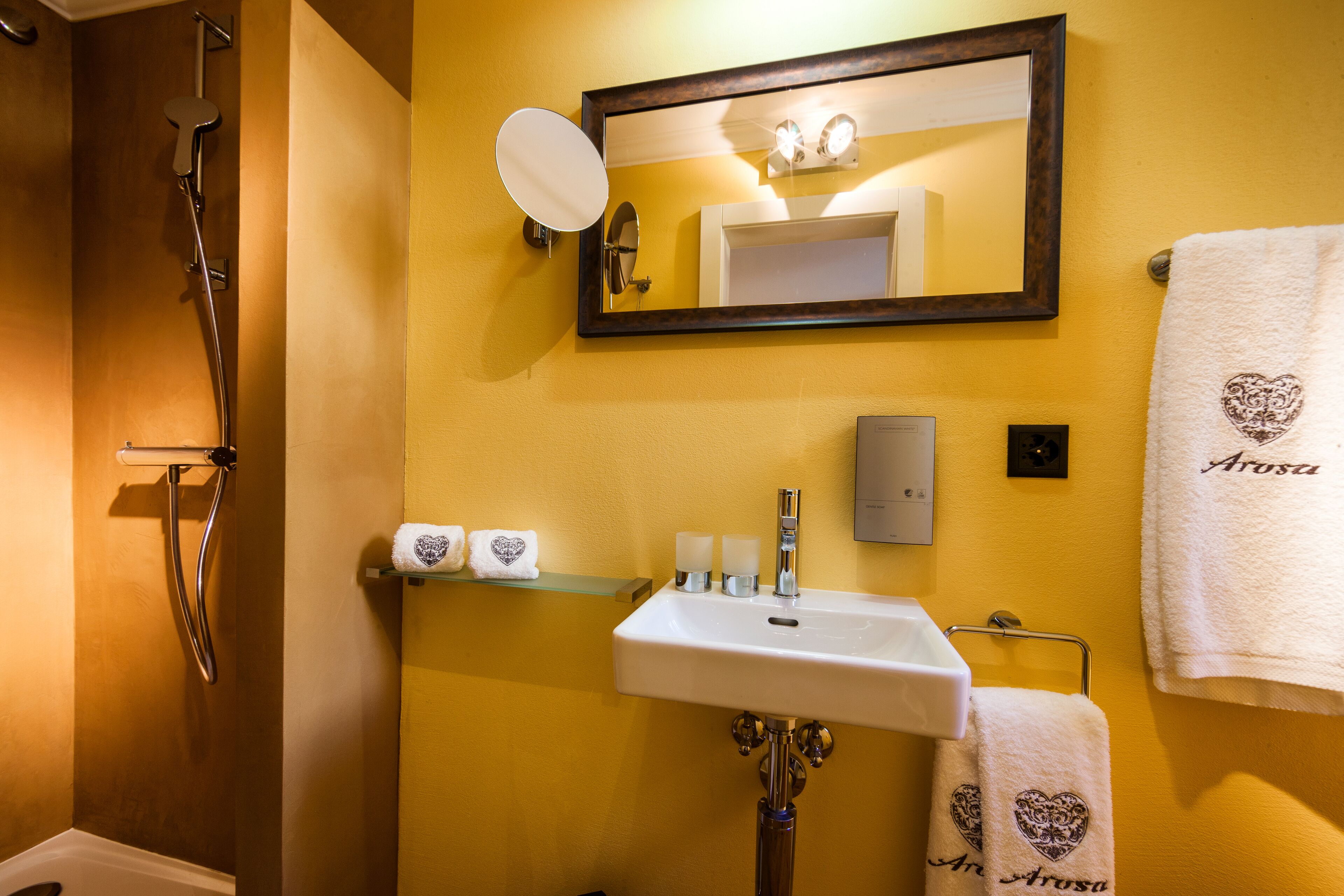Une salle de bain équipée d’une douche, d’un lavabo, d’un miroir et de serviettes.