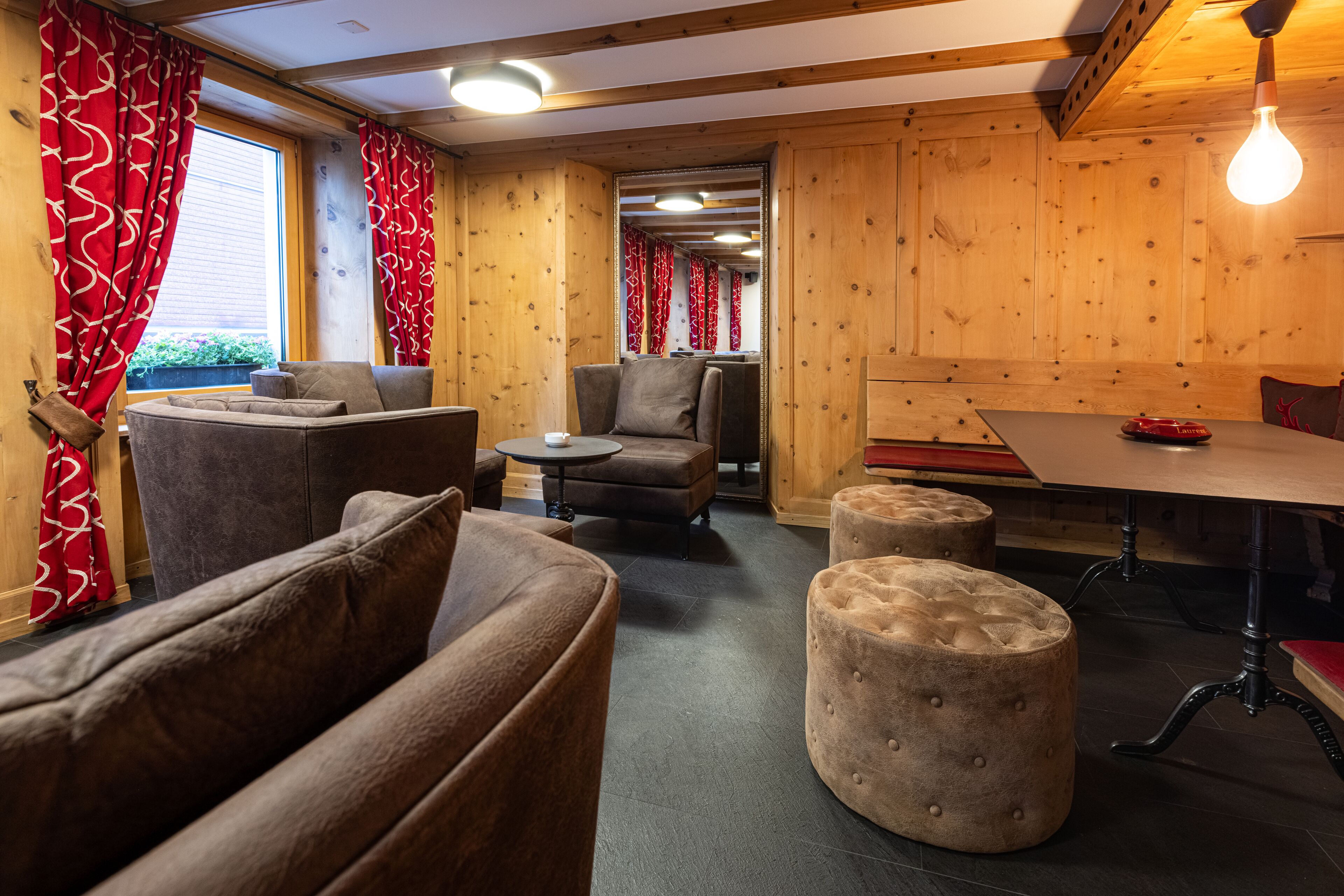 L’intérieur chaleureux d’un chalet avec des murs en bois, une table à manger et des sièges confortables.