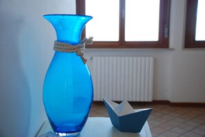 A blue vase with a rope tied around its neck and a paper boat on a table.