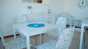 A dining area with a white table and chairs, a small cabinet with a mirror above, and a wall clock. - Cala Chiara B&B (Ortona)