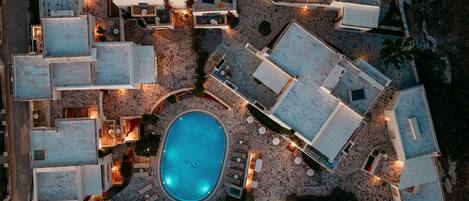 An aerial view of a resort with multiple buildings, a swimming pool, and outdoor seating areas.