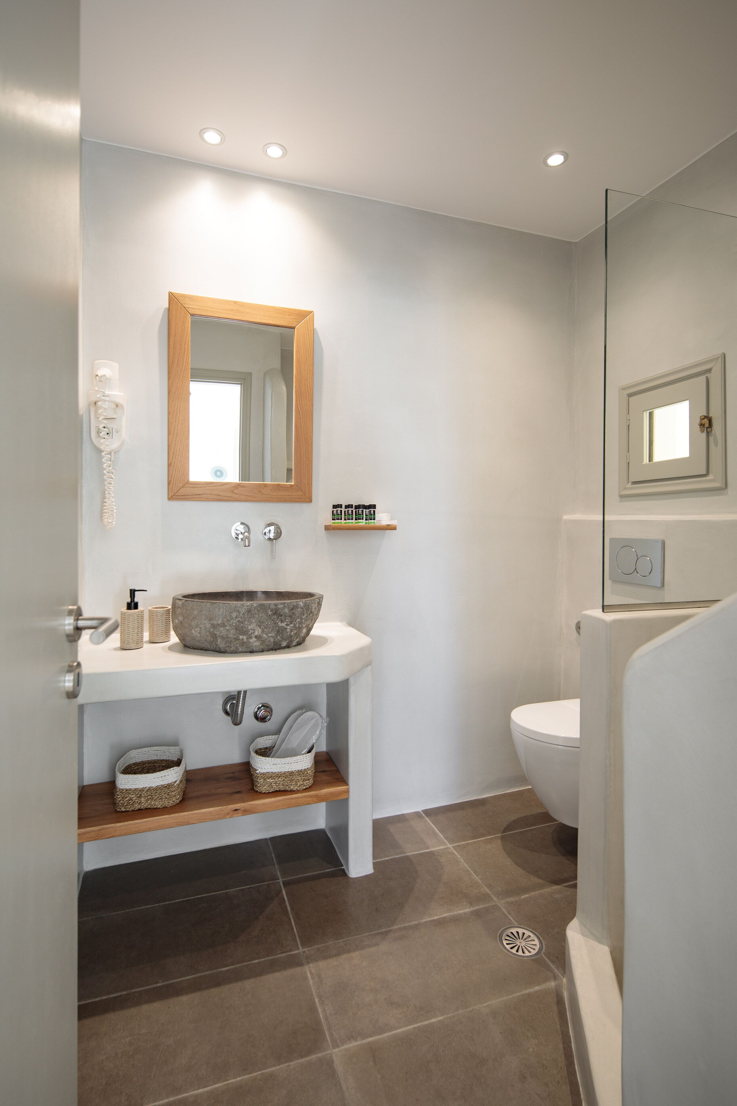 A modern bathroom with a white sink, wooden vanity, and a large mirror.