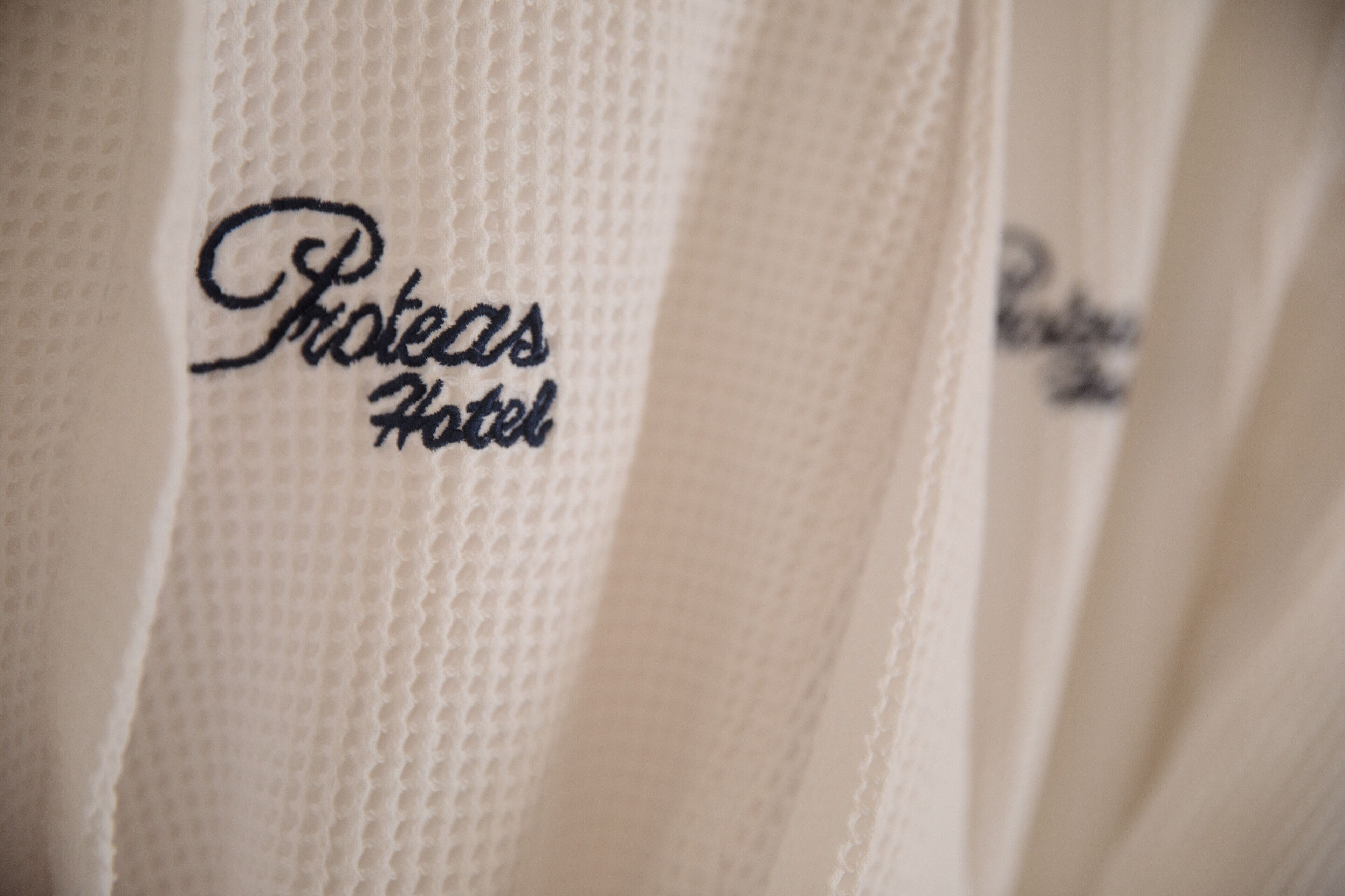 A close-up of a white fabric with embroidered text 'Proteas Hotel'.