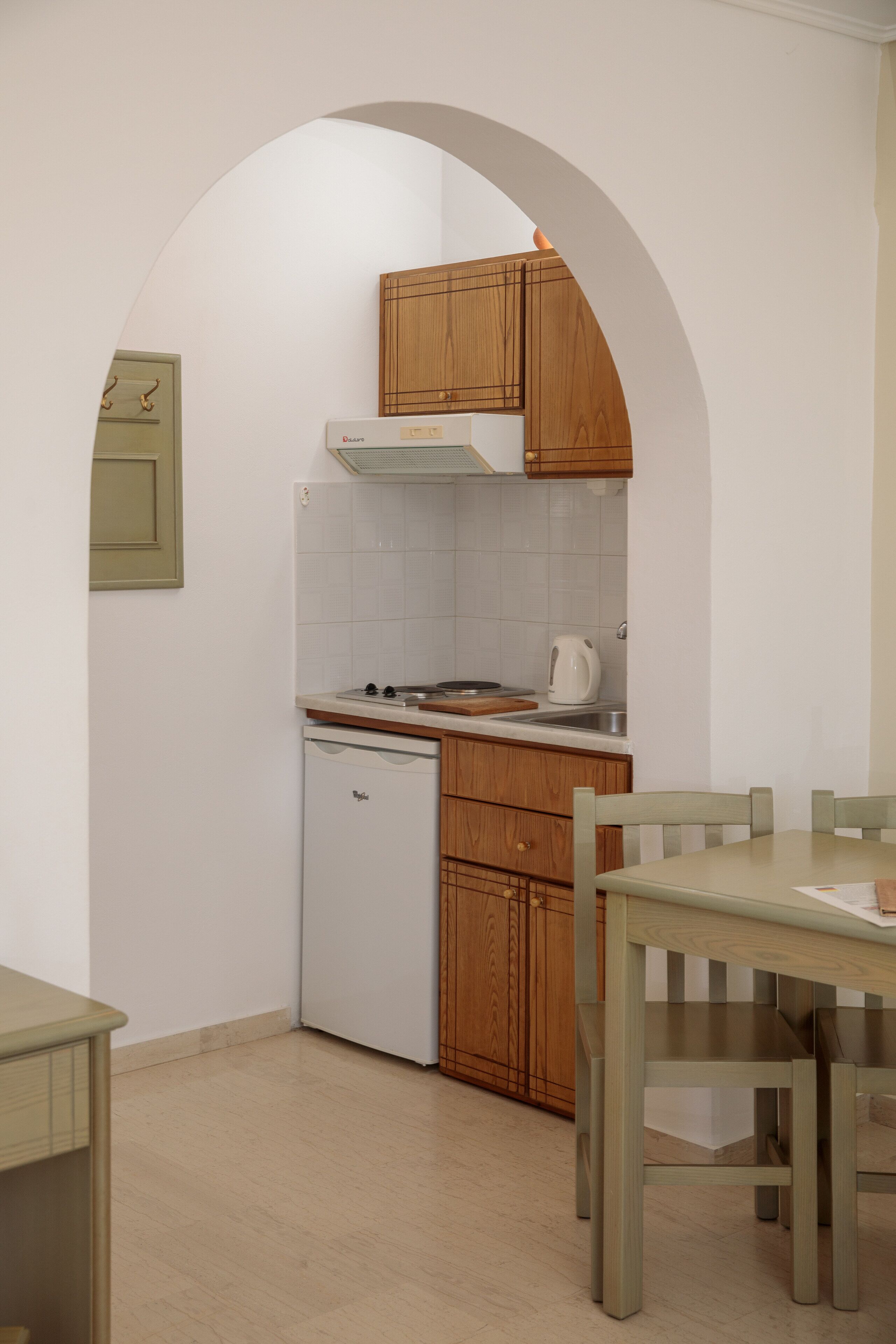 A compact kitchen with wooden cabinets, a white refrigerator, and a small dishwasher.