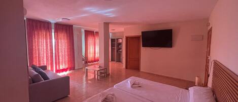 Ein Hotelzimmer mit Bett, Sofa, Fernseher und Schreibtisch.