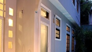 A swimming pool with a ladder, a door, and windows on a building. - Villa Raha (Colombo)