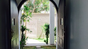 An arched entrance with a view of a garden and a gated area. - Villa Raha (Colombo)