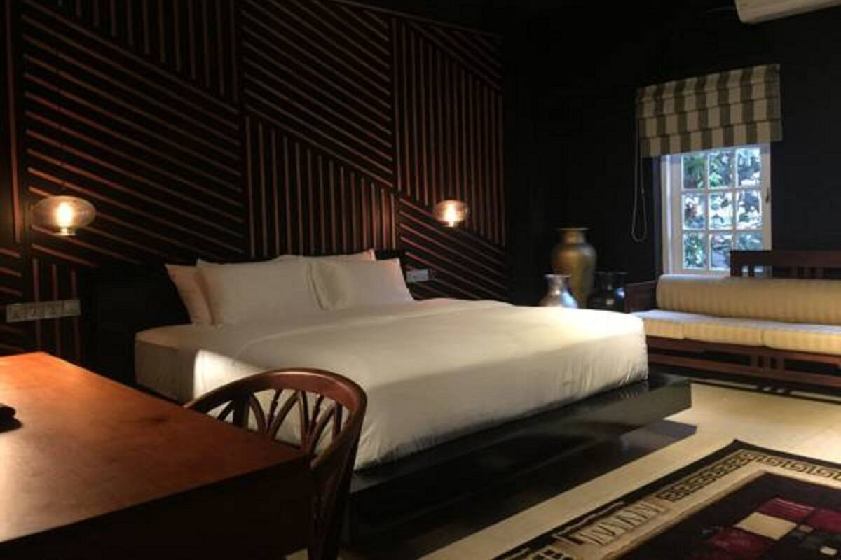 Une chambre à coucher comprenant un lit, une table en bois, une chaise, une fenêtre donnant sur un beau paysage et un vase décoratif.