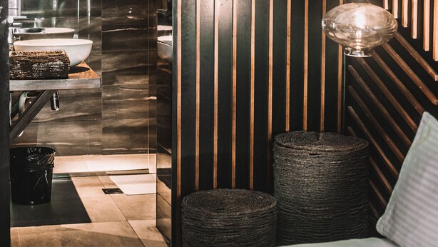 A modern bathroom with a large mirror, a sink, and a toilet. There are two round wicker baskets on the floor. - Villa Raha (Colombo)