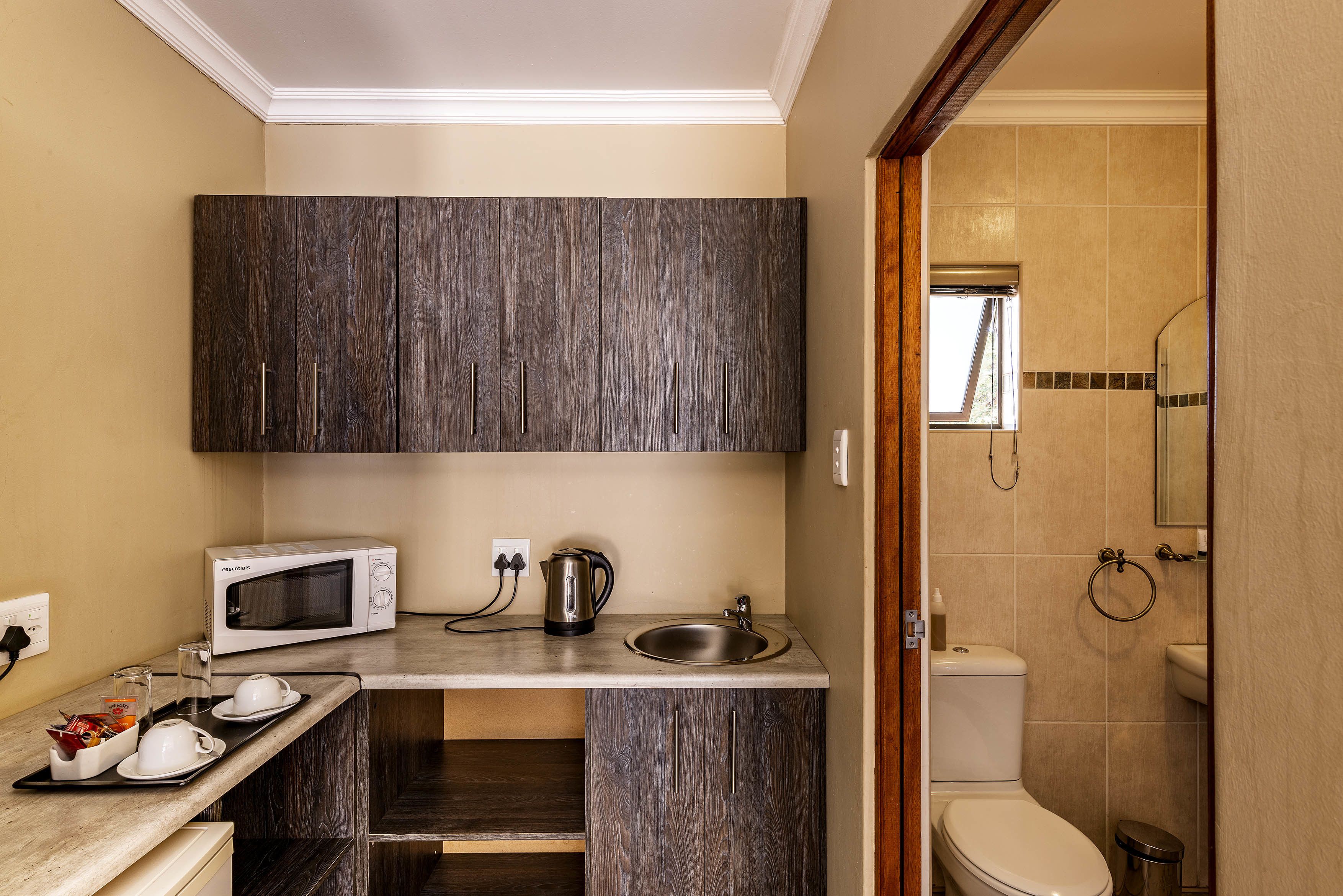 A compact kitchen with a microwave, kettle, and sink.