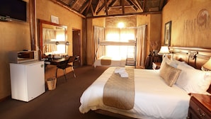 A hotel room with a bed, a desk, a television, a microwave, and a small refrigerator.
