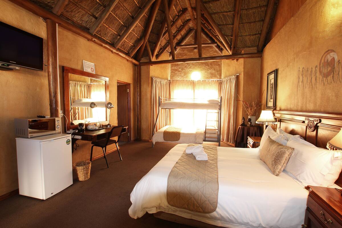 Ein Hotelzimmer mit einem Bett, einem Schreibtisch, einem Fernseher, einer Mikrowelle und einem kleinen Kühlschrank.