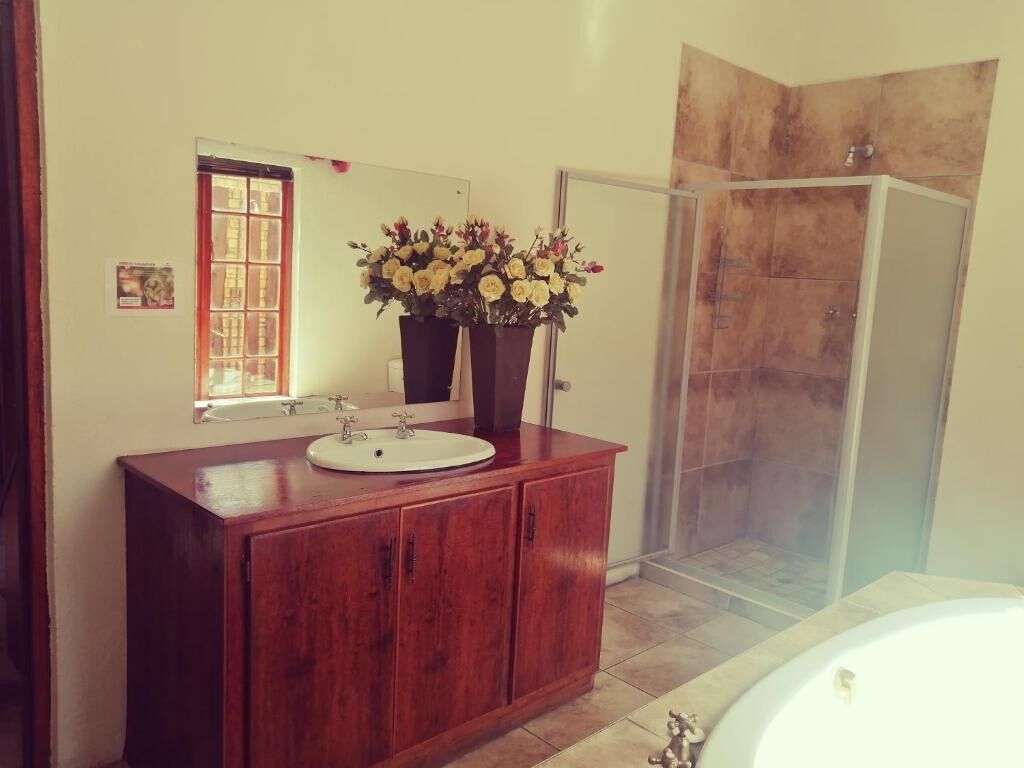 A bathroom with a wooden vanity, a sink, a mirror, a shower area, and a bathtub.