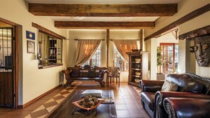 A spacious living room with a checkered floor, leather sofas, a fireplace, and a bookshelf.
