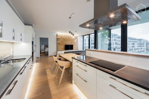 A modern kitchen with a large island, built-in appliances, and a view of the city.