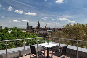 A terrace with a table and chairs, overlooking a historic building with domes and spires.