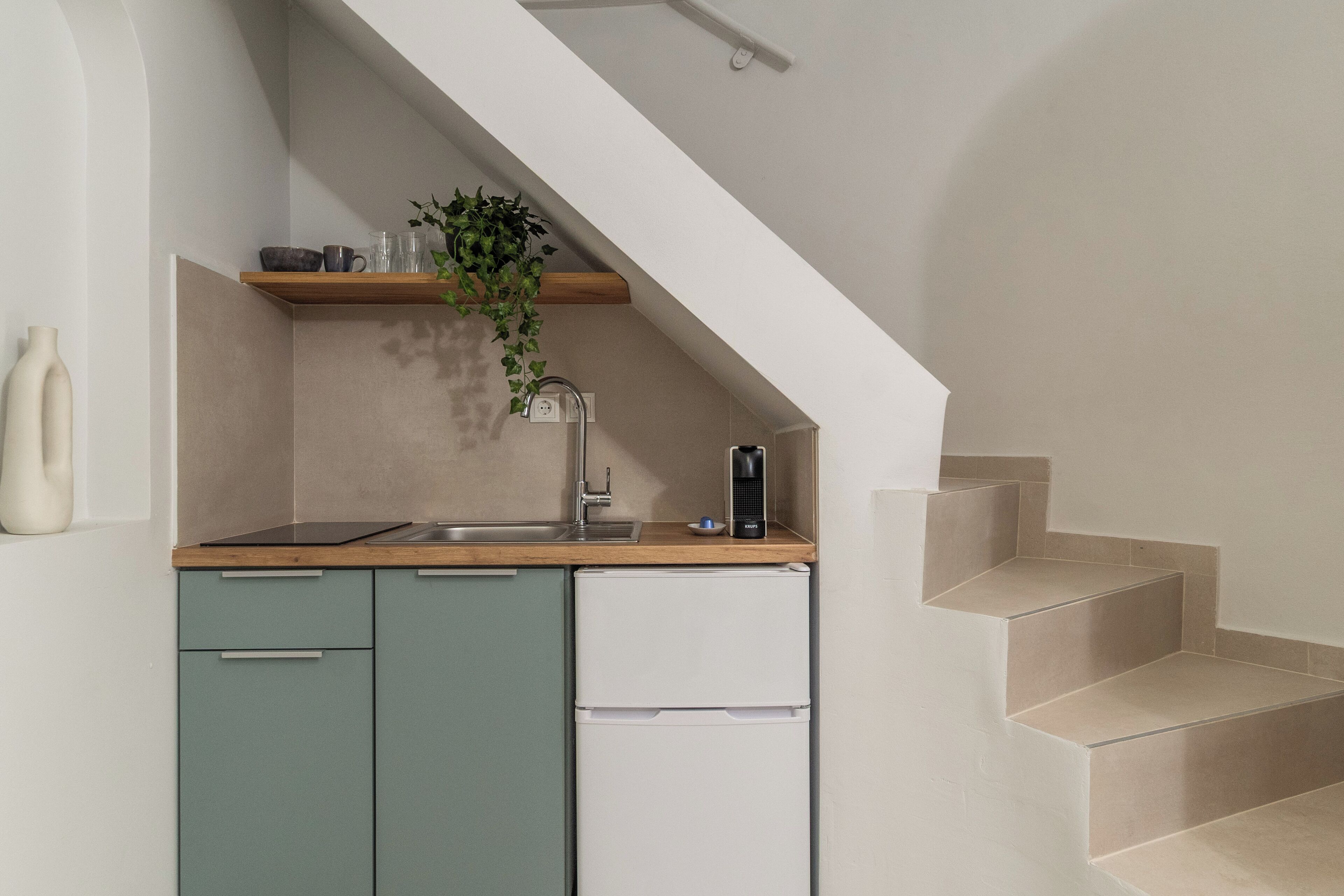 A kitchen with teal cabinets, a white refrigerator, a wooden countertop, a hanging plant, and a built-in sink.