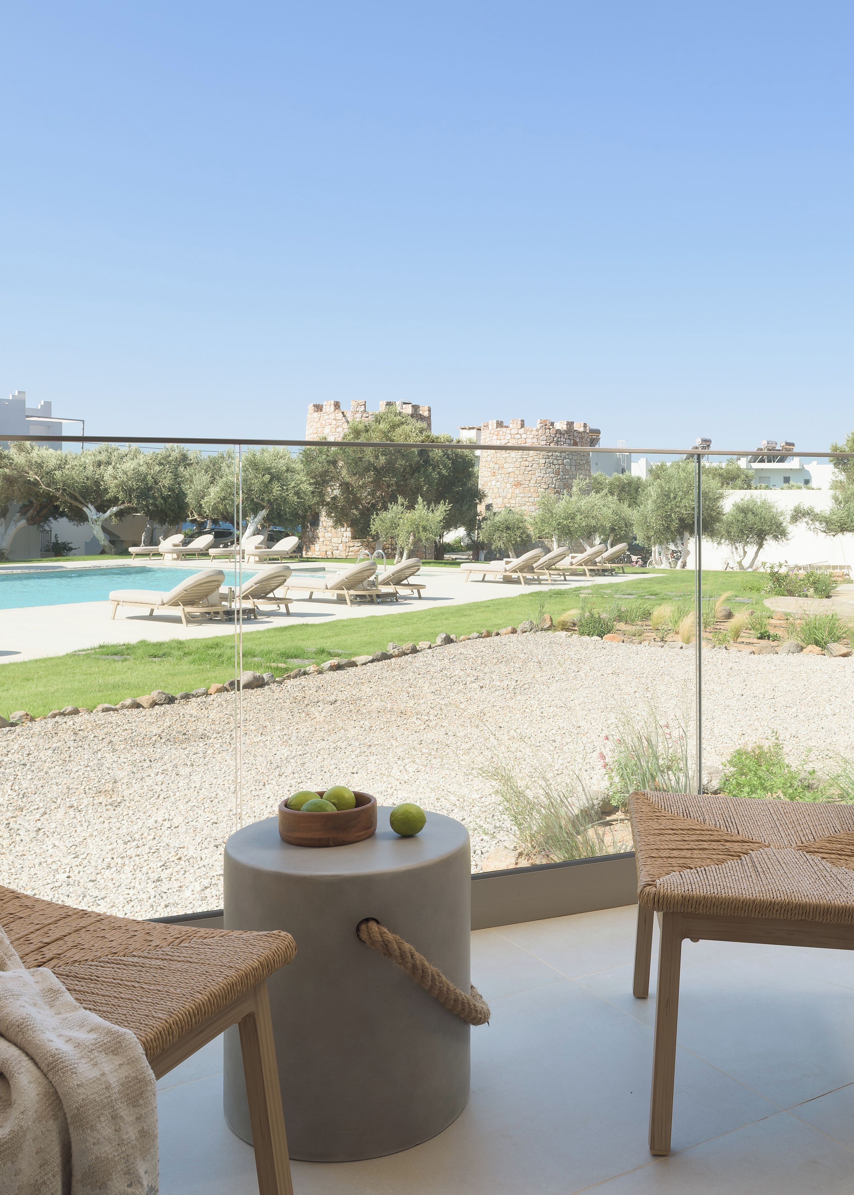 Un balcon avec une piscine, des chaises longues et une vue sur un château.