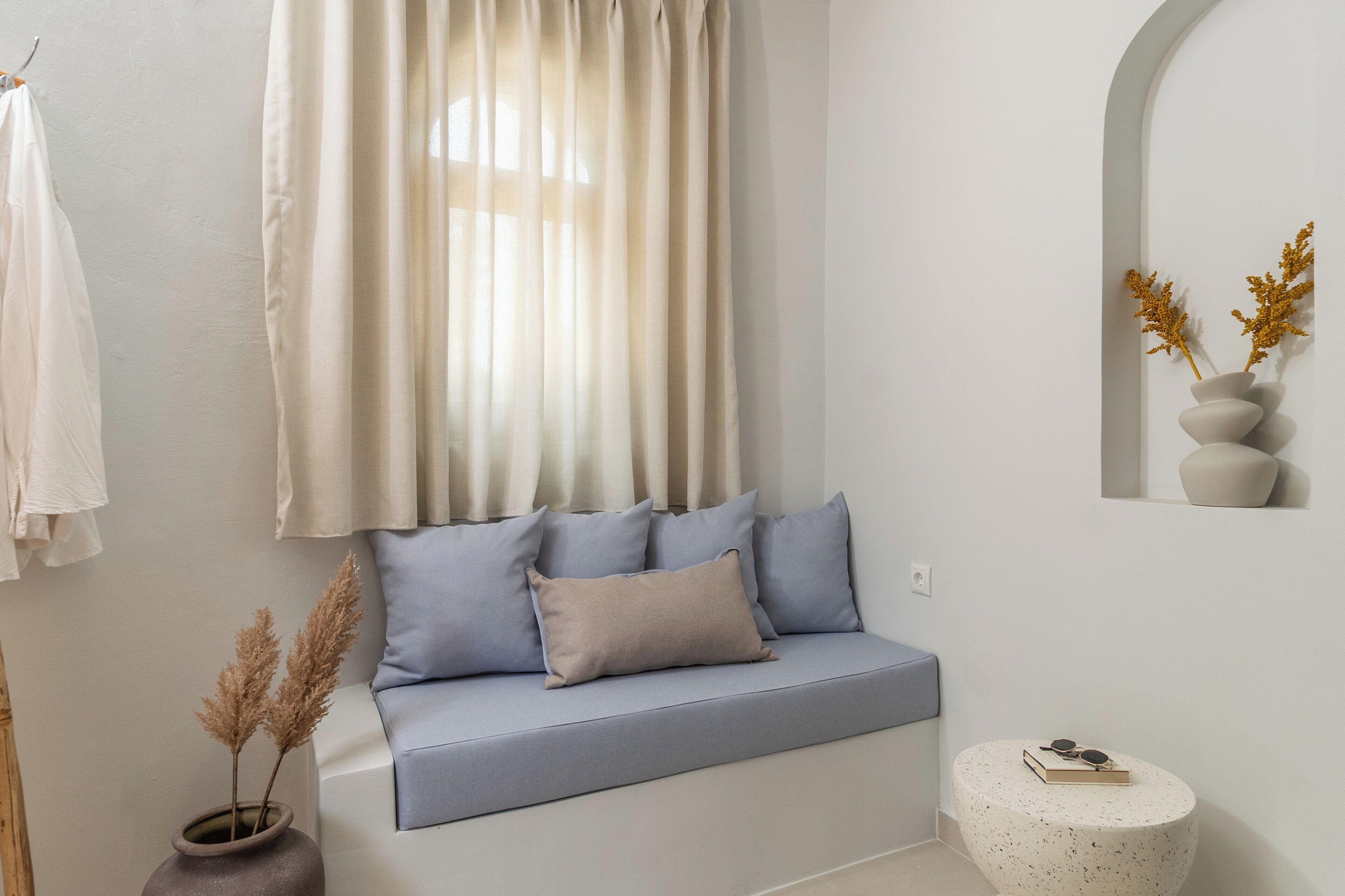 A modern living room with a sofa, a round side table, and a vase with dried plants.