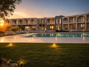 A modern hotel with a swimming pool, multiple balconies, and a stone facade. - Fata Morgana Studios & Apartments (Sfakia)