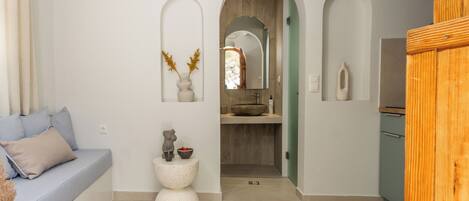 A modern interior with a sofa, a decorative stool, and a mirror.