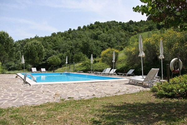 Una piscina al aire libre de temporada, sombrillas
