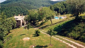 Una casa de piedra con piscina y montañas al fondo.