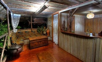Una habitación rústica con un banco de madera, una mesita y un muro decorativo.