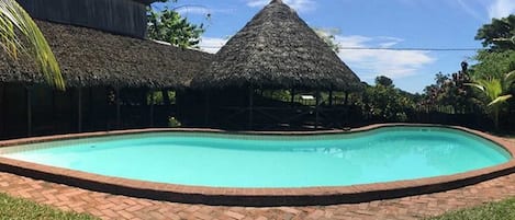 Alberca al aire libre, sombrillas en la alberca y camastros