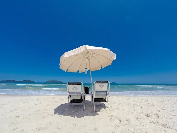 Di pantai, pasir putih, kerusi lepak pantai, payung 