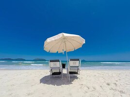 Aan het strand, wit zand, ligstoelen aan het strand, parasols