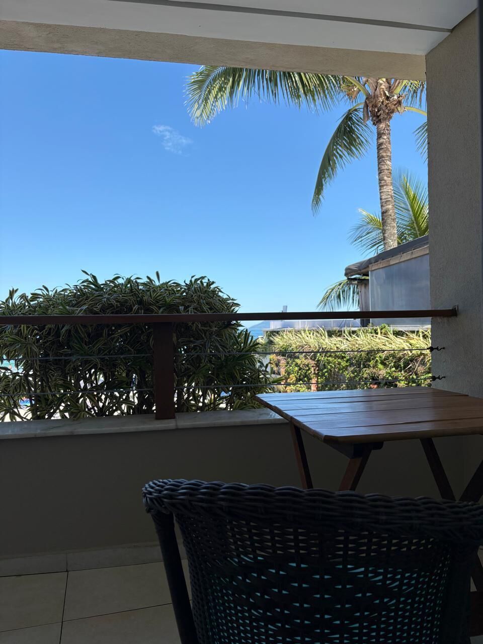 A balcony with a view of palm trees and a clear sky.