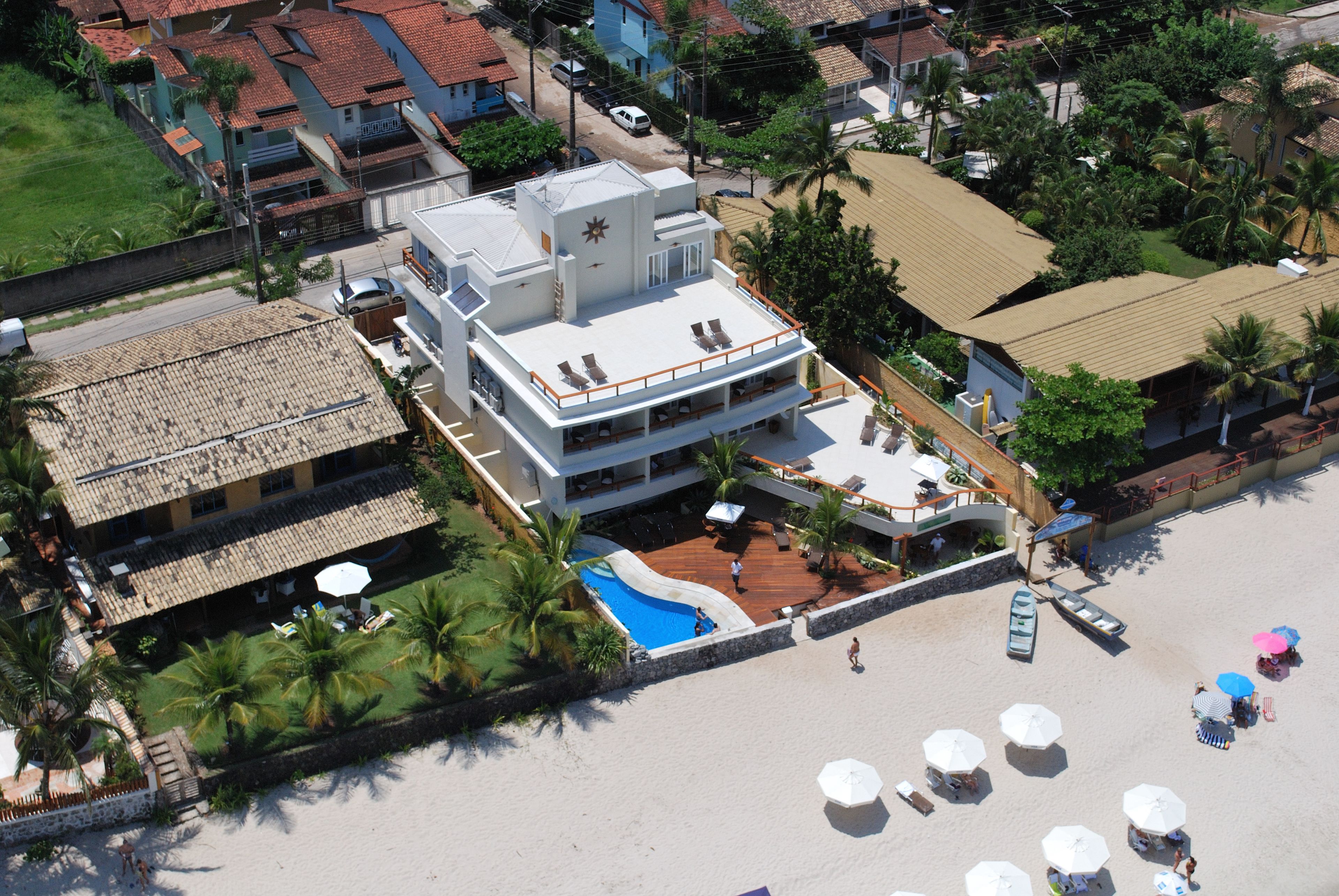 Un resort con piscina, sombrillas de playa y vista al mar.