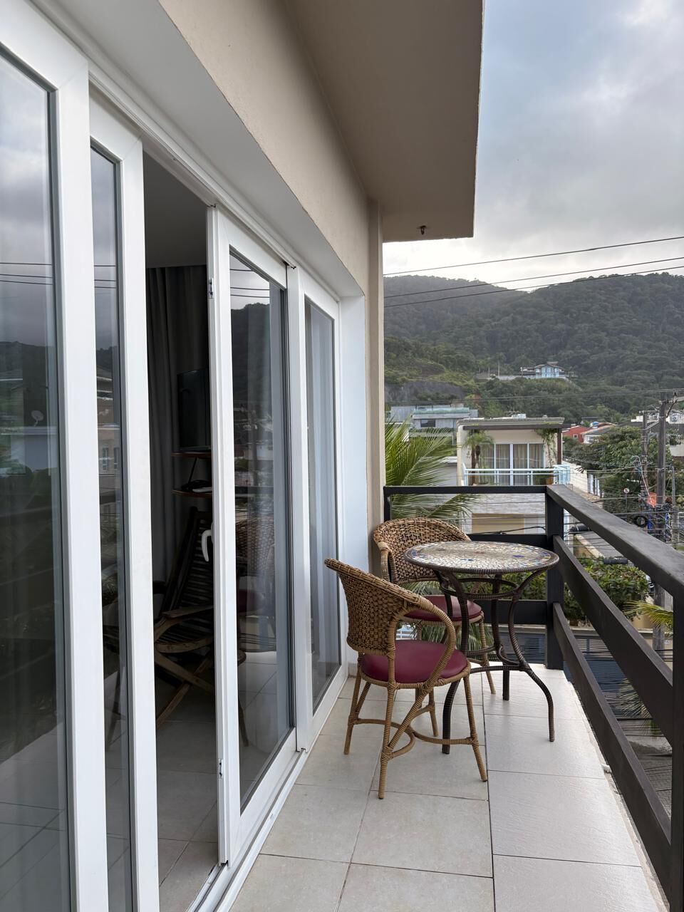 Ein Balkon mit Blick auf eine gebirgige Landschaft, eine Schiebetür und zwei Korbstühle.