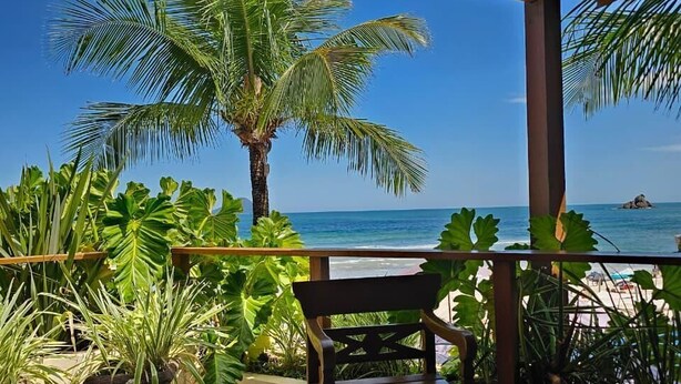 A covered outdoor area with a wooden ceiling, a view of the ocean, and potted plants. - Juquehy La Plage (São Sebastião)