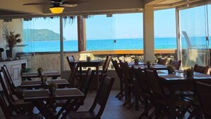 A restaurant with wooden furniture and large windows overlooking the ocean. - Juquehy La Plage (São Sebastião)