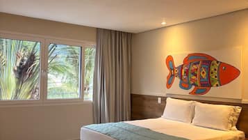 Una habitación de hotel con una cama, una ventana con cortinas y un cuadro de peces de colores en la pared.