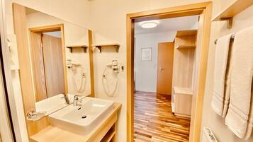 Ein modernes Badezimmer mit Waschbecken, Spiegel, Handtuchhalter und Duschbereich.