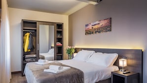 A hotel room with a large bed, a wardrobe, a bedside table with a lamp, and a painting on the wall. - Hotel Gardenia (Sirmione)
