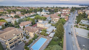 A residential area with a swimming pool, a church, and a road. - Hotel Gardenia (Sirmione)