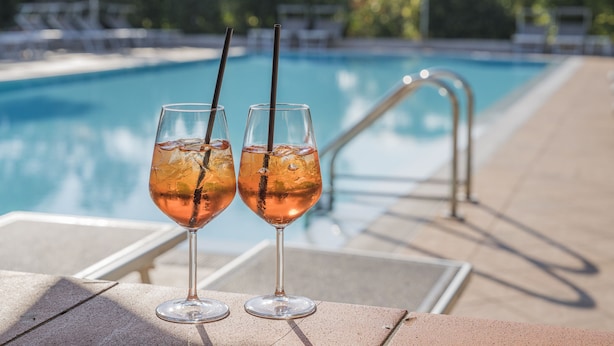 Two glasses of a pink beverage with straws on a poolside table. - Hotel Gardenia (Sirmione)