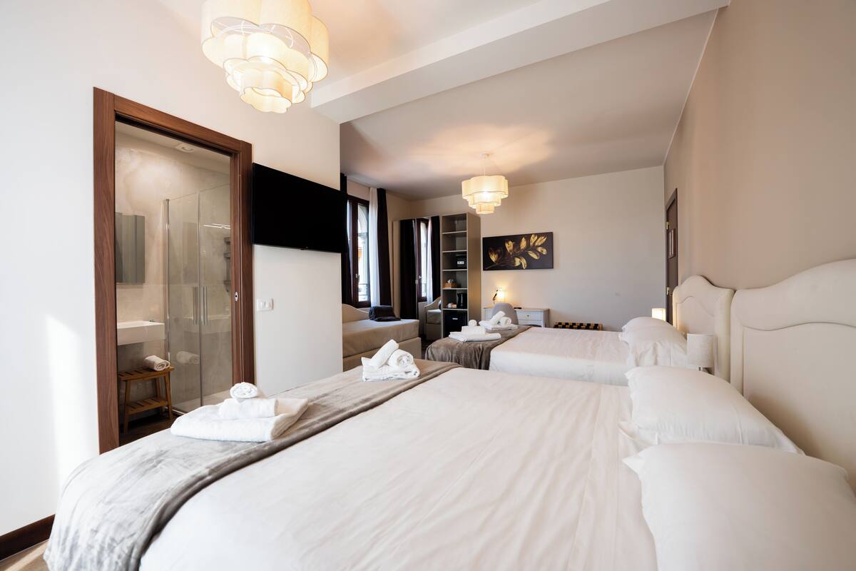 Quarto de hotel com duas camas, chuveiro, área de estar e um espelho grande.