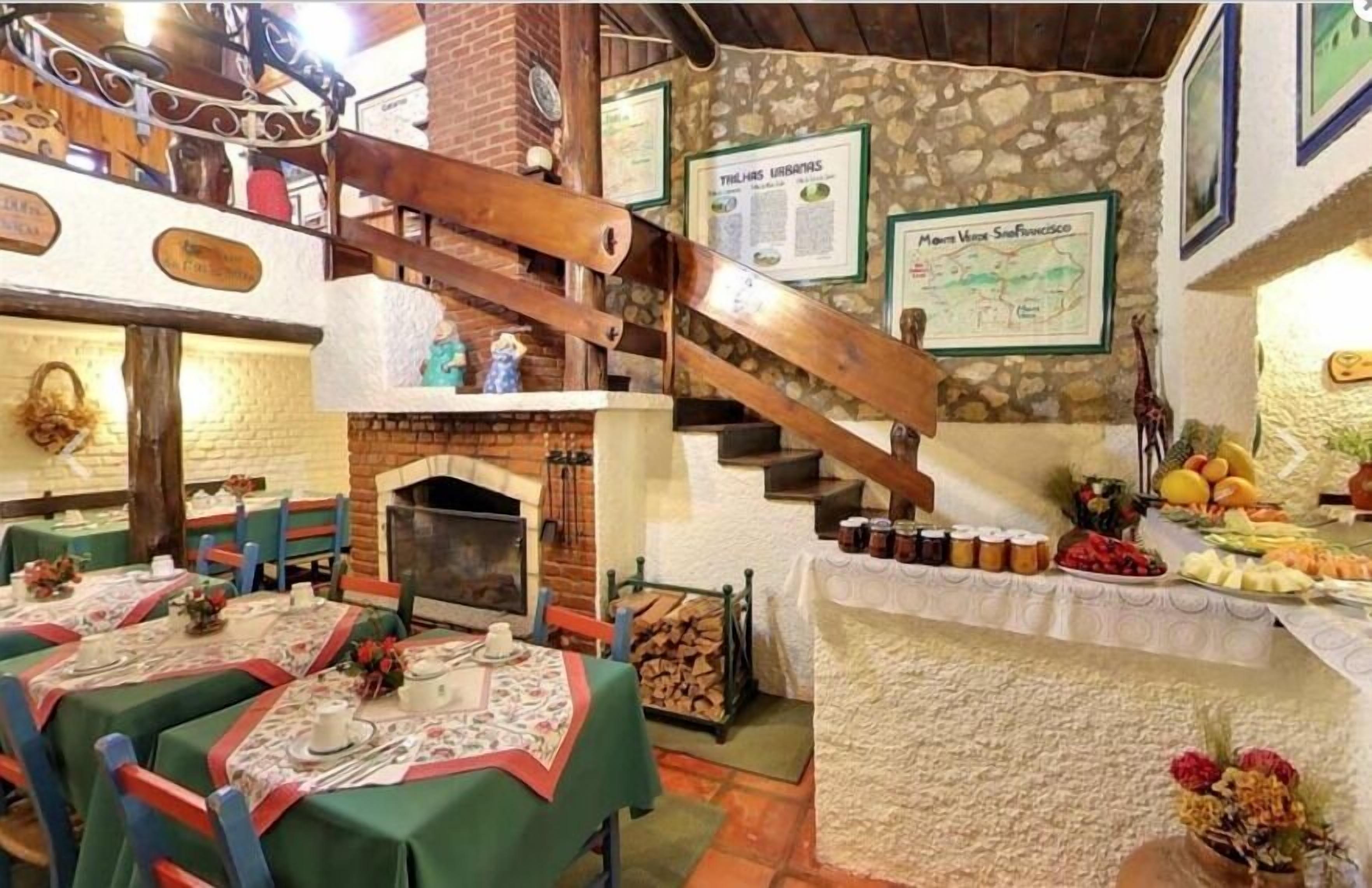 Un comedor rústico con mesas de madera, chimenea y una escalera.