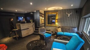 A modern lounge area with leather sofas, a coffee table, and a reception desk. - Hôtel Kanaï (Lille)