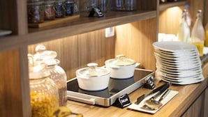 A breakfast bar with various food items, including fruits, condiments, and cooking utensils. - Hôtel Kanaï (Lille)