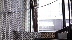 A staircase with patterned wallpaper and a view of the outside through a window. - Hôtel Kanaï (Lille)