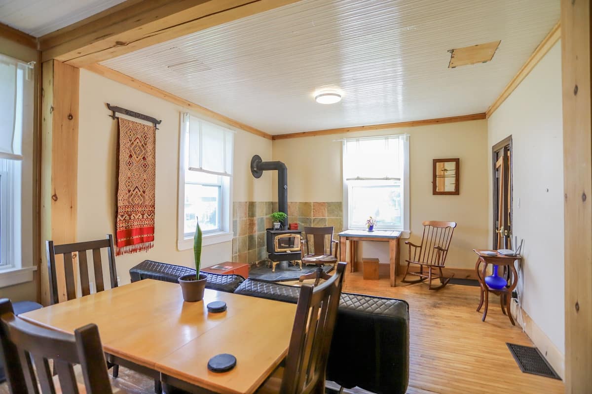 A cozy cabin interior with a dining area, a fireplace, and a small table with chairs.