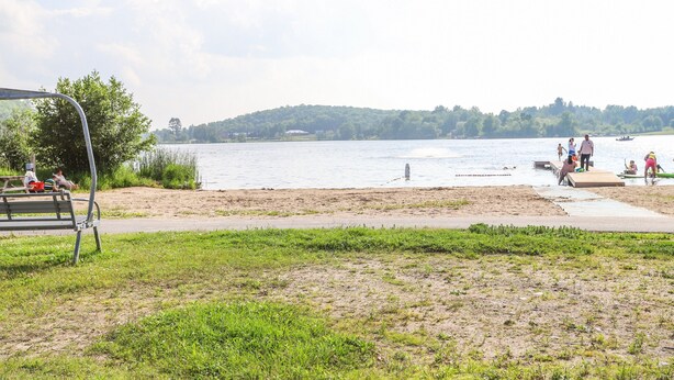Un parc au bord du lac, avec une pelouse, un banc en métal et une scène pour les événements.