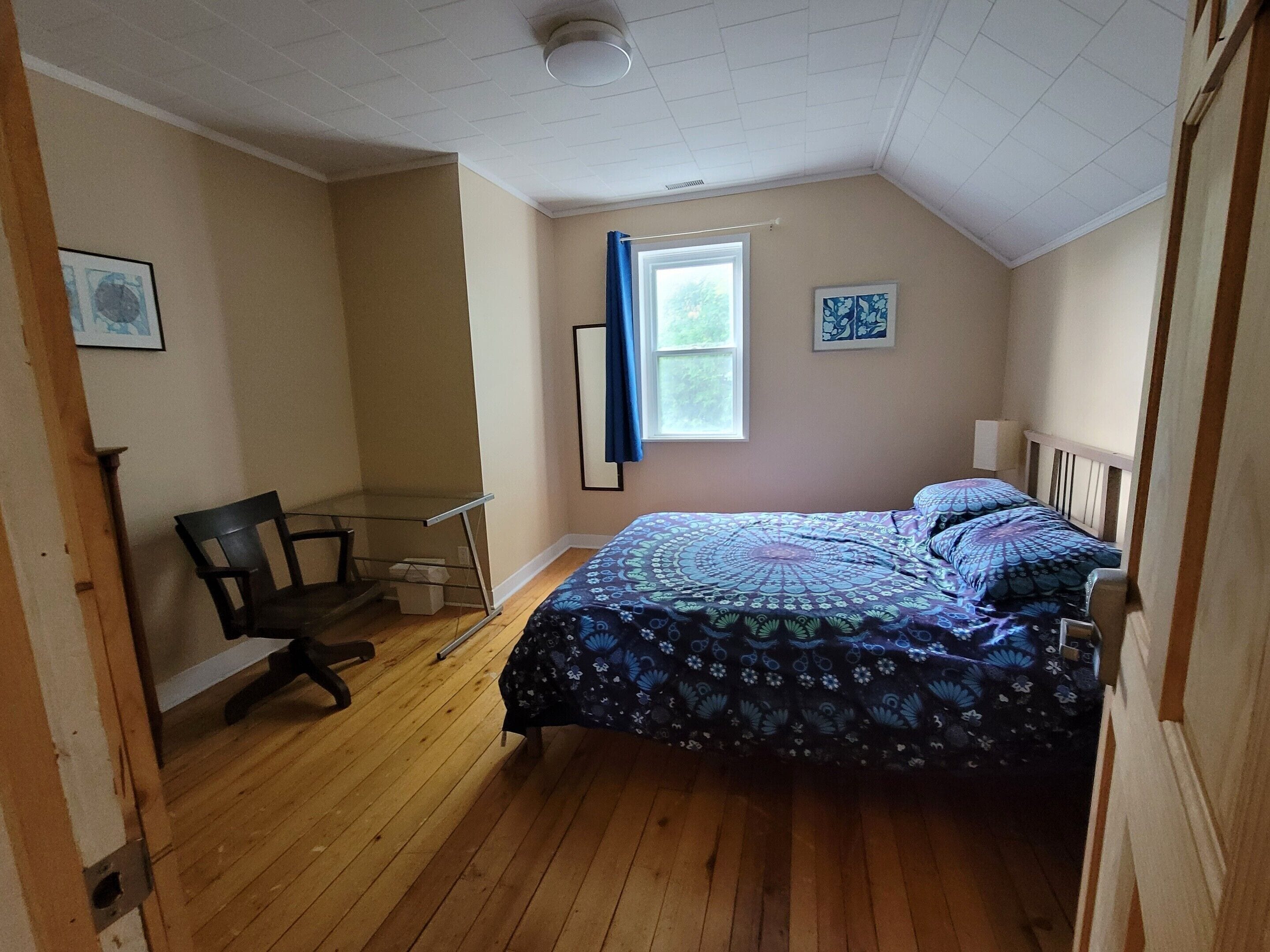 A bedroom with a bed, a desk, and a chair.